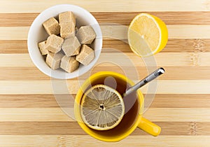 Cup of tea with lemon and bowl of lumpy sugar