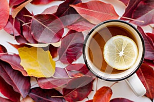Cup of tea with lemon close-up on a background of red leaves