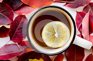 Cup of tea with lemon close-up on a background of red leaves