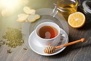 Cup of tea with lemon, ginger, honey and honey stick on wooden rustic table