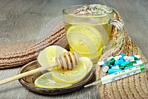 Cup of tea with lemon, pills, a thermometer and a warm scarf. vitamin tea. cold and flu remedy.