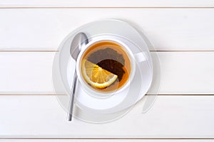 A cup of tea with lemon on a saucer