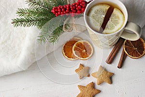 A Cup of tea with lemon on the table close-up surrounded by Christmas decorations and homemade cakes.