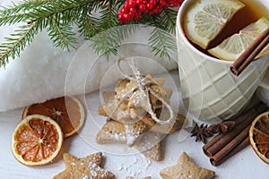 A Cup of tea with lemon on the table close-up surrounded by Christmas decorations and homemade cakes.
