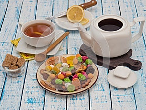 Cup of tea with lemon, a teapot and dried fruits on a wooden table