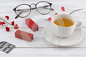 A cup of tea, lipsticks, necklace and eyeglasses