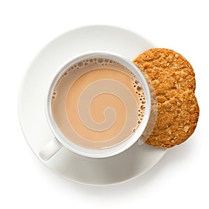 Cup of tea with milk and one and half crunchy oat and wholemeal biscuits isolated on white. White porcelain. Top view