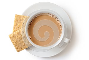 A cup of tea with milk and two square shortbread biscuits isolated on white from above. White ceramic cup and saucer.