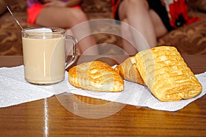 A Cup of tea with milk and various pastries on the table during tea. The people in the background