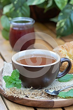 Cup of tea with mint, croissant and jar of jam