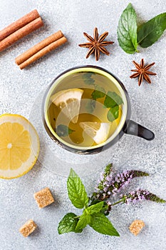 Cup of tea, mint and lemon, brown sugar cinnamon and anise on a grey table