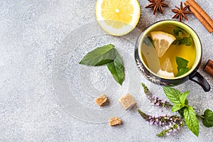 Cup of tea, mint and lemon, brown sugar cinnamon and anise on a grey table with copy space