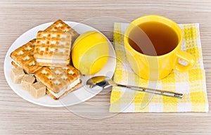 Cup of tea on napkin, biscuits, lemon and lumpy sugar