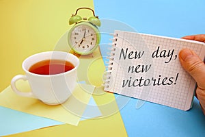 Cup of tea and a notebook with the inscription New day, new victories photo