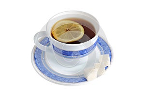 A cup of tea with one slice of lemon within and refined sugar on