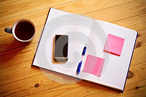 Cup of tea, pen, opened organizer and smartphone