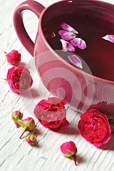 Cup of tea and rose flowers and buds on white wood