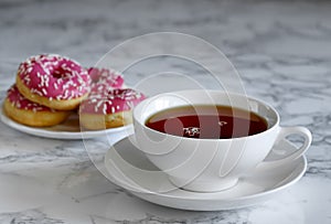 A cup of tea and a saucer with donuts