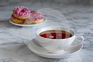 A cup of tea and a saucer with donuts