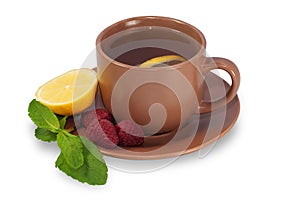 Cup of tea on a saucer with lemon, raspberry and mint leaves iso