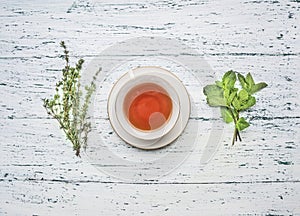 Cup of tea on a saucer with a set of herbal tea thyme, mint, lemon grass wooden rustic background top view close up