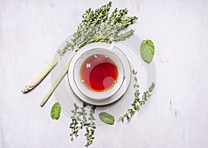 Cup of tea on a saucer with a set of herbal tea thyme, mint, lemon grass on wooden rustic background top view close up
