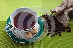 A Cup of tea with shortbread cookies on a green background. Coffee beans with burlap