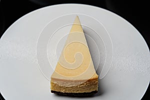 Cup of tea and slice of cheese cake on white plate on table