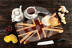 Cup of tea, sliced lemon and a bun on a cutting board