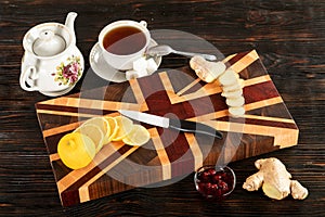 Cup of tea, sliced lemon and a bun on a cutting board