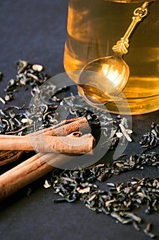 Cup of tea with spoon. Herbs and cinnamon sticks on black background. Close up healthy beverage. lifestyle scene food and drinks.