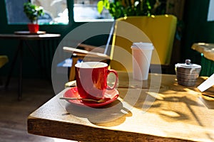 A cup of tea with a spoon on a wooden table in a coffee shop.