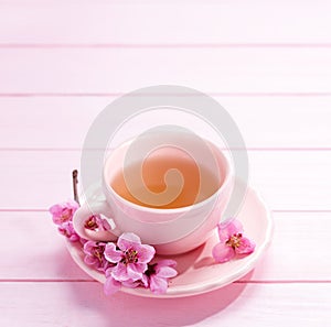 Cup of tea and spring  flowers  Peach blossom on light pink wooden table. Selective focus