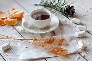 A cup of tea, sticks with sugar cristals, marshmallows and some elements of Christmas decor