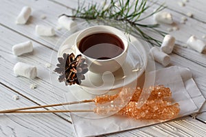 A cup of tea, sticks with sugar cristals, marshmallows and some elements of Christmas decor