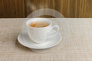 Cup of tea on tablecloth and wooden background