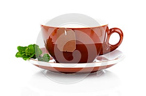 Cup of tea with tea bag and mint plant