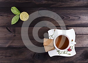 A cup of tea with tea cookies and fresh lime on wooden background