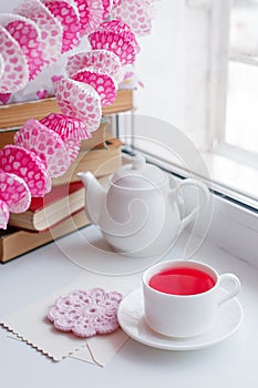 Cup of tea and teapot on white windowsill, morning springtime concept