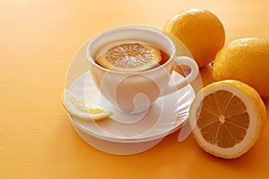 A cup of tea with three lemons on a yellow background, space for text