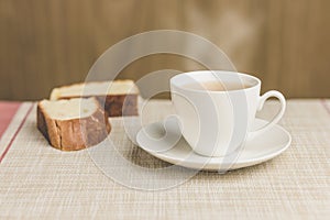 Cup of tea with two bread on tablecloth and wooden background