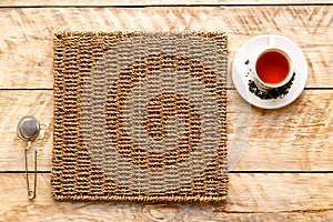 Cup of tea on a wicker mat with strainer
