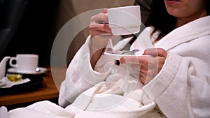 Cup of tea in womans hands drinking tea resting lying in armchair in spa sauna.