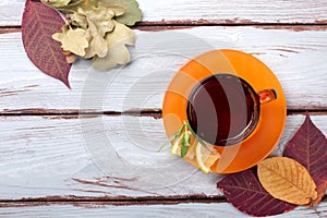 Cup of tea on a wooden background with autumn leaves. Top view