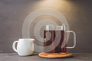 Cup of tea on wooden support and creamer on black table/cup of tea on wooden support and white creamer on black table