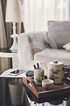 Cup of tea on wooden tray on a round table with sofa in living r