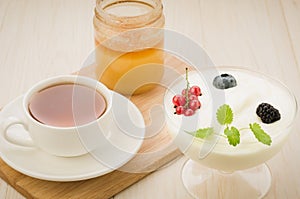 Cup tea, yogurt with berries and honey jar on wooden background/cup tea, yogurt with berries and honey jar on wooden background.