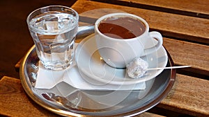 Cup of Turkish coffee with glass of water.