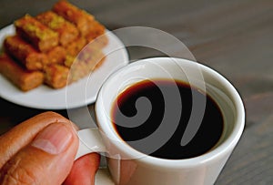 Cup of Turkish Coffee in Hand with Blurry Baklava Pastries in the Backdrop