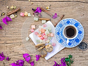 A cup of Turkish coffee with sweets and spices on a wooden surface